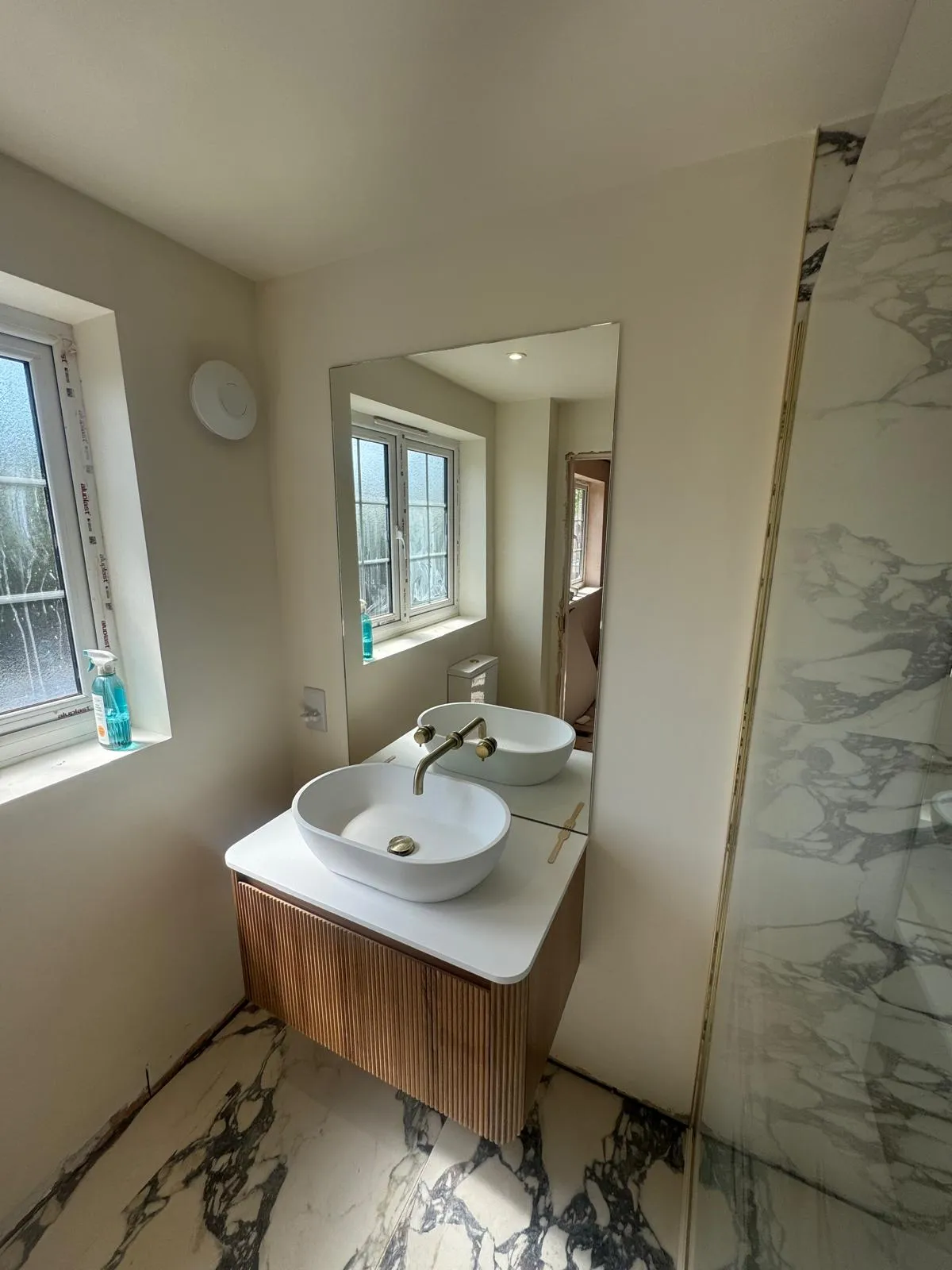 A bathroom with a countertop basin and marble effect floor