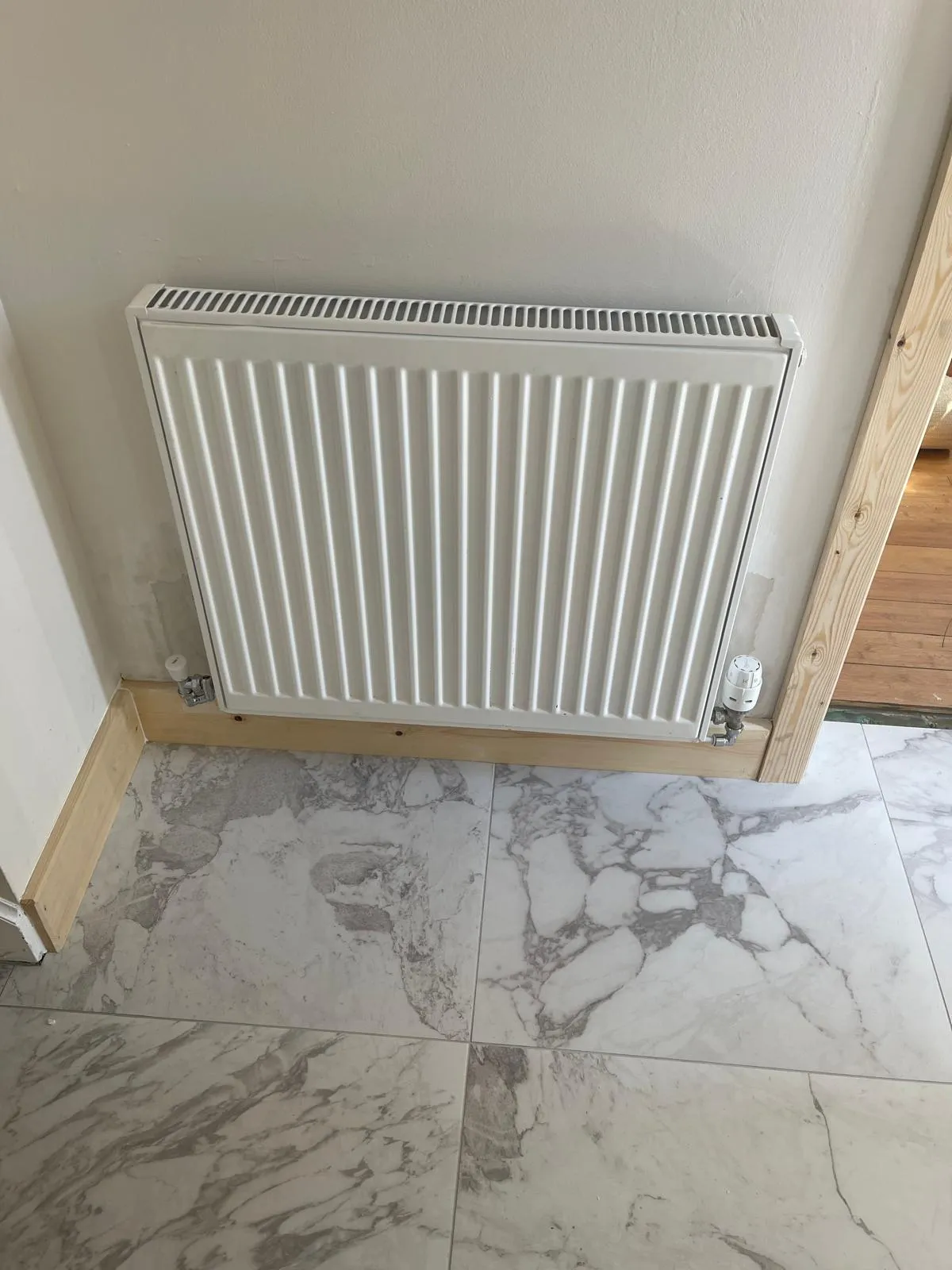 A new radiator fitted in a room with a marble effect floor