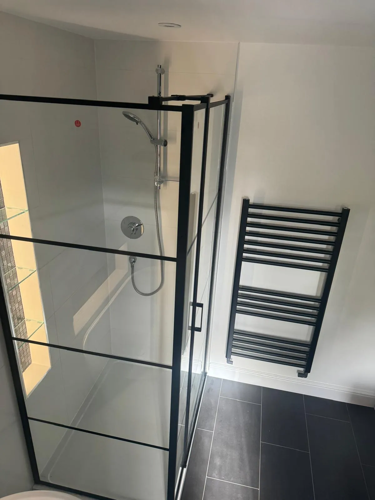 A black framed shower enclosure with a matching towel radiator
